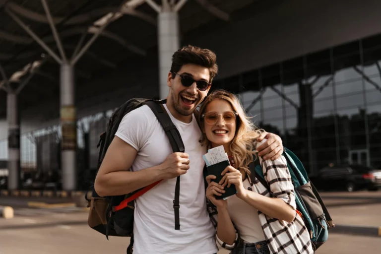 young-brunette-man-smiles-widely-hugs-his-attractive-girlfriend-couple-travelers-holds-backpacks-passports-airport-background